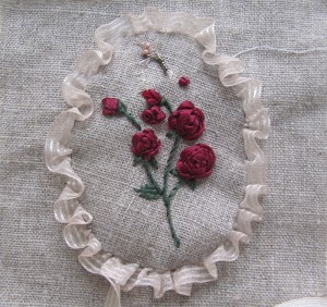 Un "médaillon" froufrouté, orné de roses brodées au ruban, en médaillon 